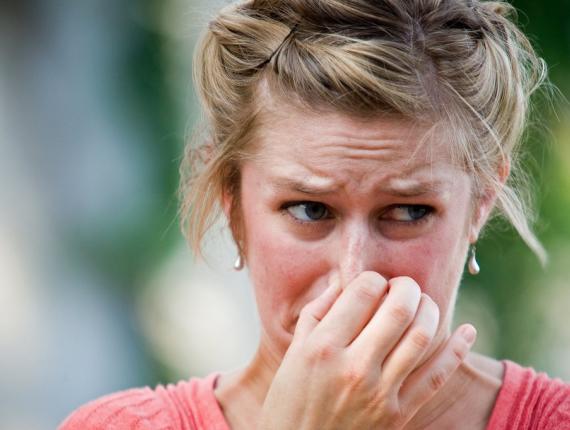 Vrouw die neus dichtknijpt vanwege stank